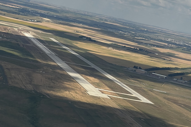 Turning from base to final under fair weather cumulus to runway 33 with 20 knot headwinds at Dickinson, North Dakota on Day 2, with a new main runway under construction.